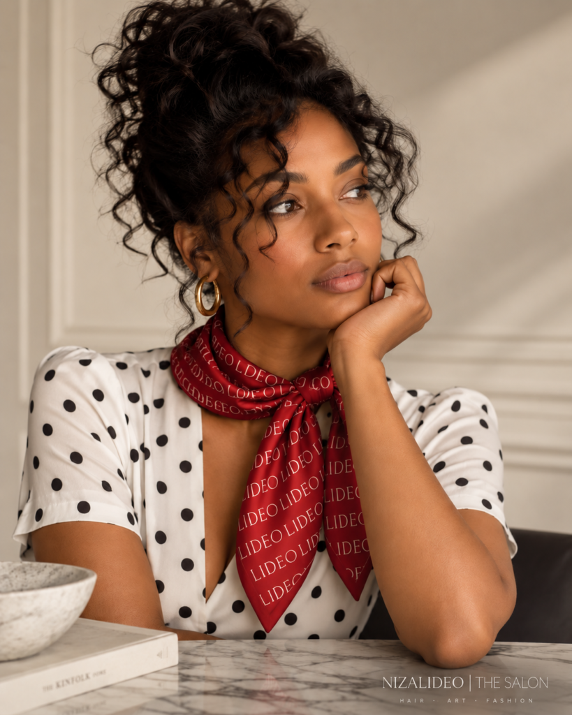 Woman thoughtfully assessing her haircut, wearing a red LIDEO scarf, for NIZALIDEO | THE SALON.